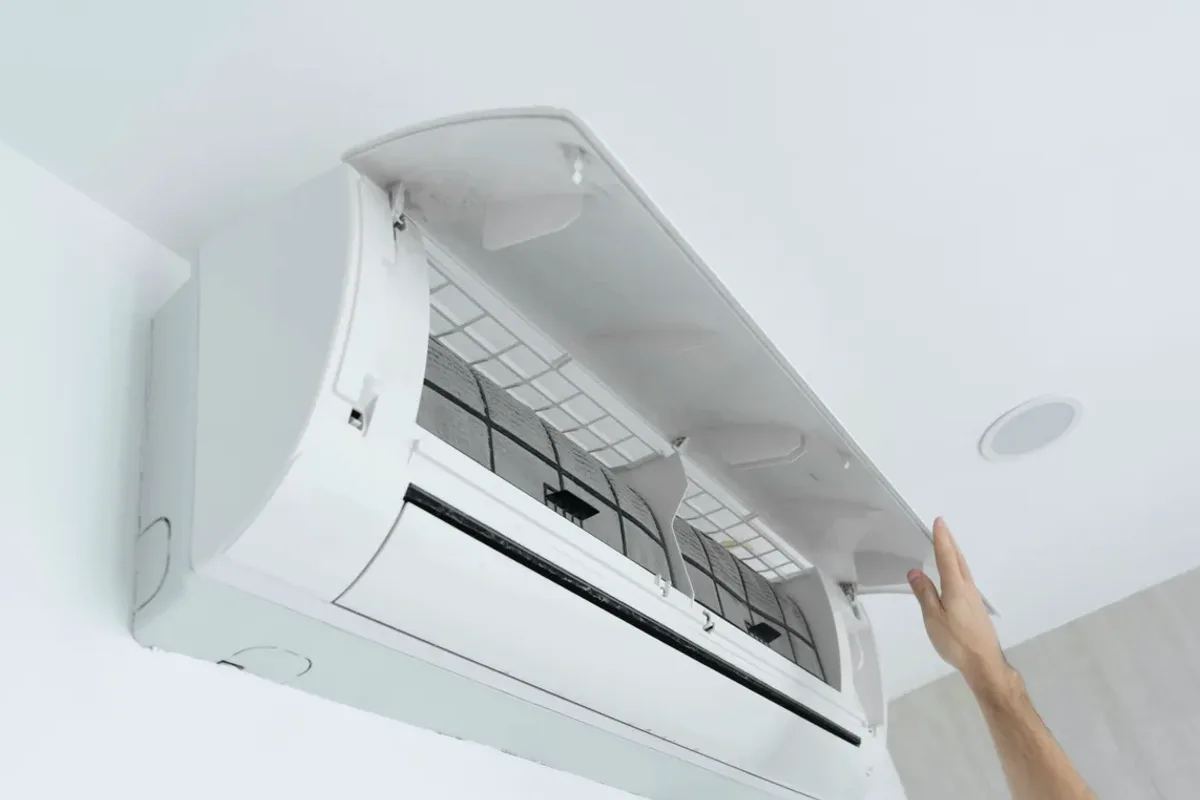 Hand opening the cover of a wall-mounted ductless air conditioner